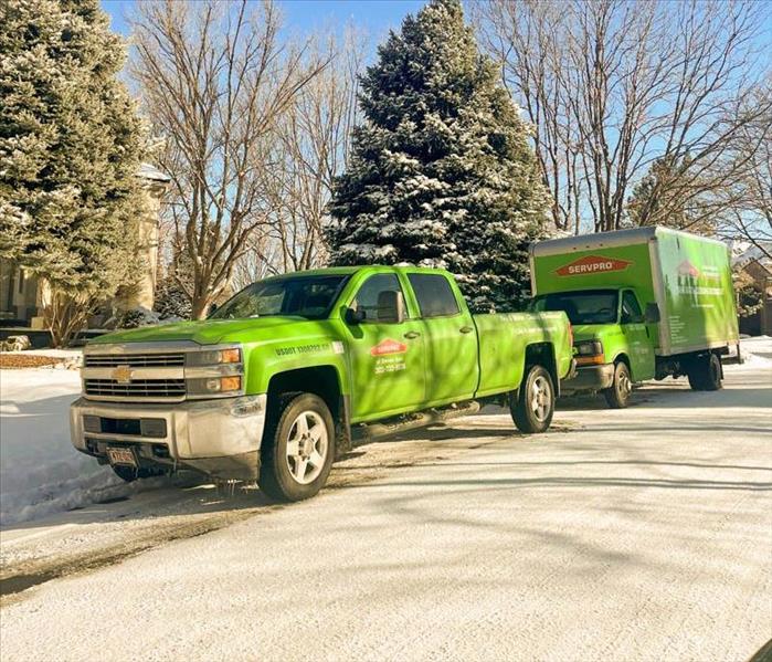 SERVPRO green trucks parked outside of job in the snow