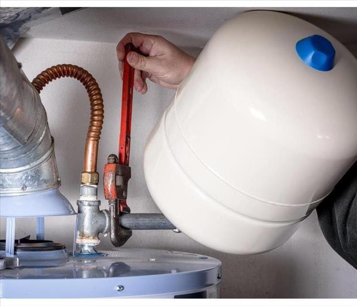 Plumber installs compression tank on hot water heater